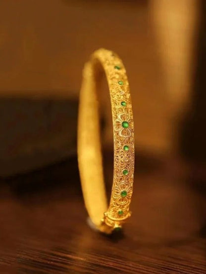 Bracelet en acier avec pierres précieuses vertes dorées et motif floral de style ethnique.