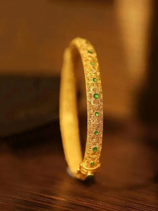 Bracelet en acier avec pierres précieuses vertes dorées et motif floral de style ethnique.